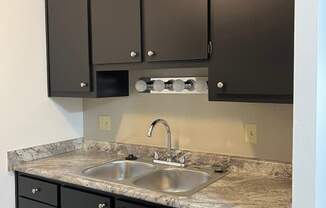 A kitchen with black cabinets and a granite countertop.
