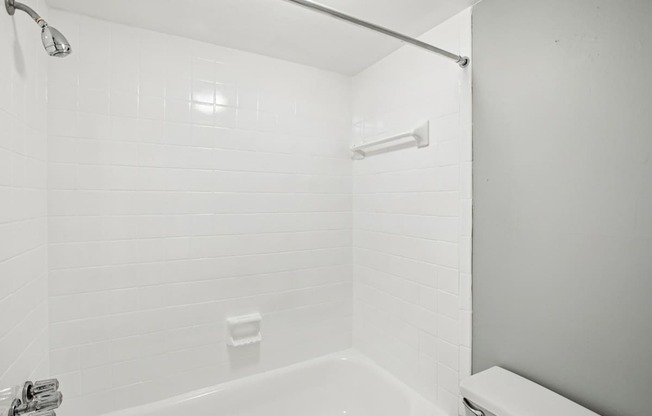 A white bathroom with a tub and toilet.
