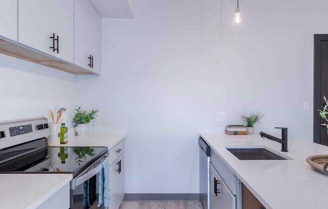 A modern kitchen with white cabinets and a wooden floor.