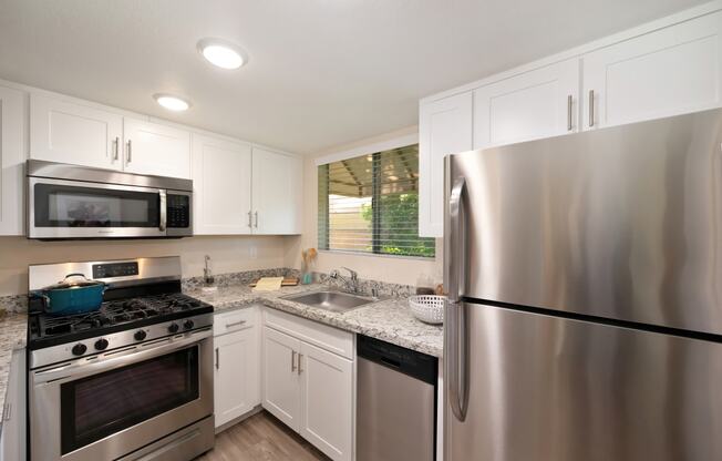 an updated kitchen with stainless steel appliances and white cabinets