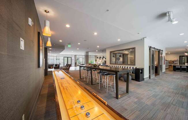 A long wooden table with several stools is in the middle of a room at Regatta Sloans Lake Apartments, Colorado