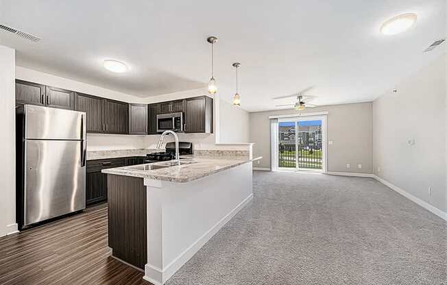 A kitchen with a refrigerator, microwave, and a countertop with a sink.