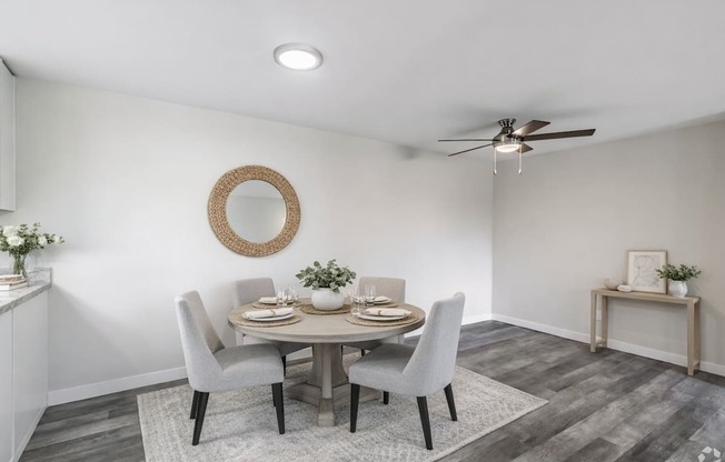 A dining room with a round table and grey chairs.