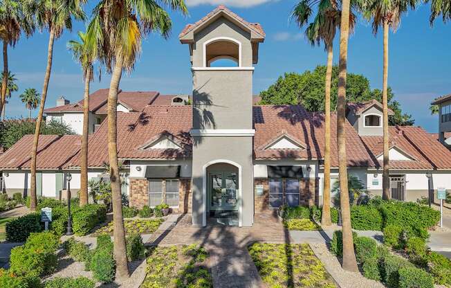A building with a tower entrance is surrounded by palm trees.