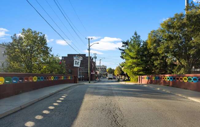 a city street with a fence and trees on the side of the road