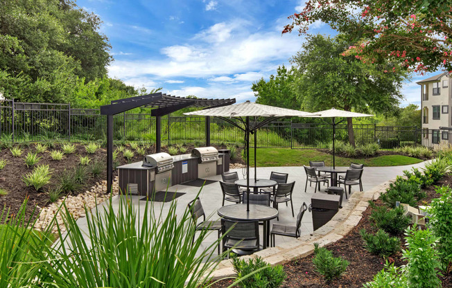 a patio with tables and umbrellas and barbecue grills