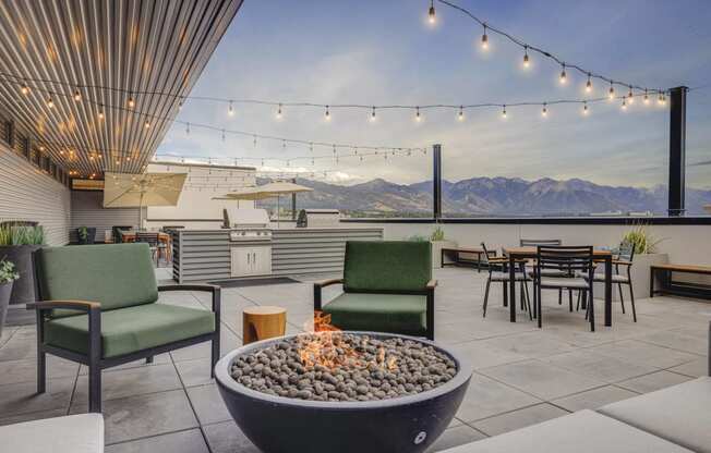 a patio with a fire pit and tables and chairs with mountains in the background