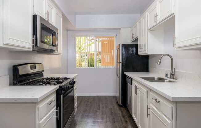 a kitchen with white cabinets and black appliances and a window