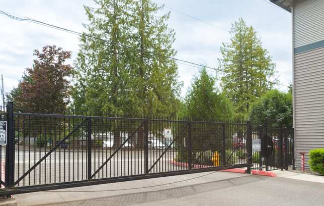 a gate to a parking lot with trees in the background