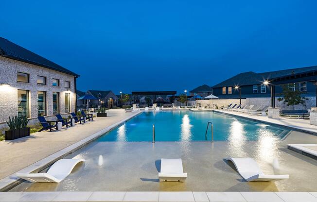 A resort-style pool at Amavi Celina with in-water loungers, expansive deck space, and evening lighting that sets the scene for relaxed nights outdoors.