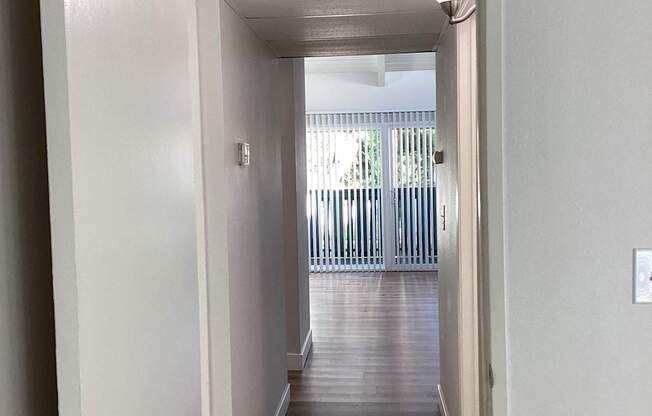 A hallway with a door on the left and a balcony on the right.