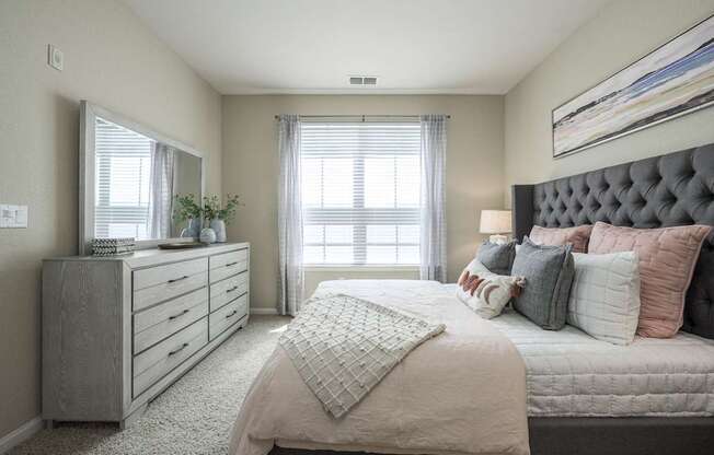 A bedroom with a large bed and a dresser with a mirror.