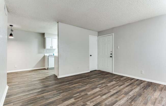 an empty living room with wood flooring and white walls