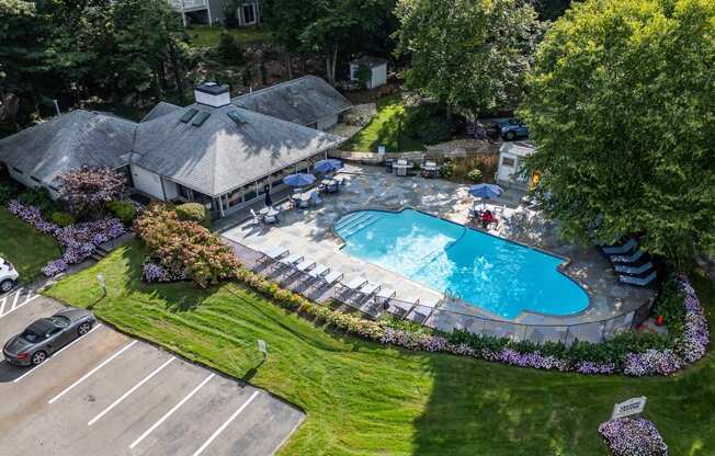 an aerial view of a swimming pool in a backyard with a pavilion and lawn