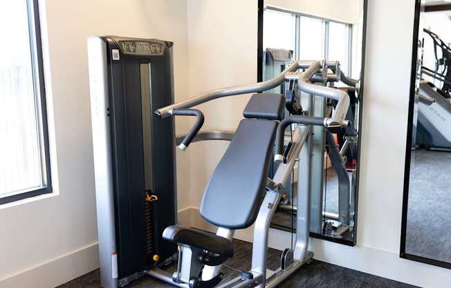 A gym with a weight machine and a mirror.
