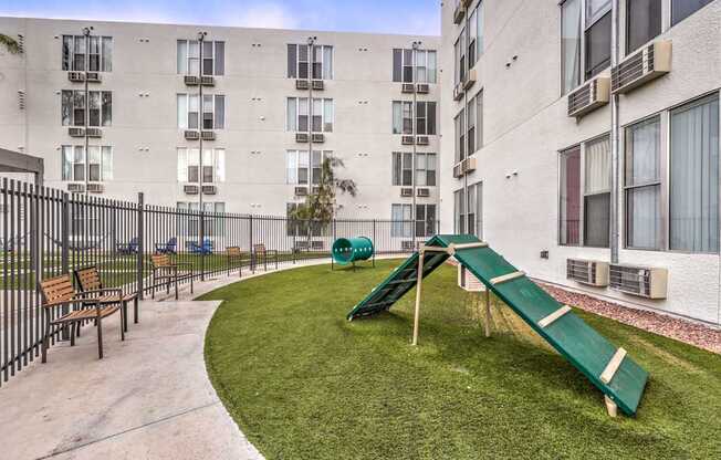 A playground with a green slide in front of a building.