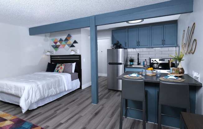 Fusion Las Vegas studio apartments in Vegas bedroom and kitchen area with navy blue cabinets, stainless steel appliances, and two seater island.