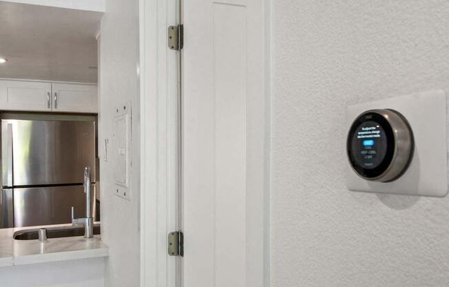 a white kitchen with a white door and a black thermostat on the wall  at Masselin Park West, Los Angeles, California