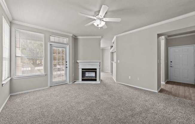 A spacious living room with a fireplace and a ceiling fan.