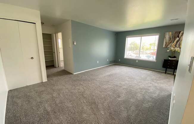 Spacious living room with window and hallway to other rooms, at Gale Gardens Apartments