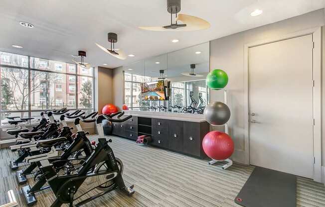 A gym with a row of treadmills and exercise balls.