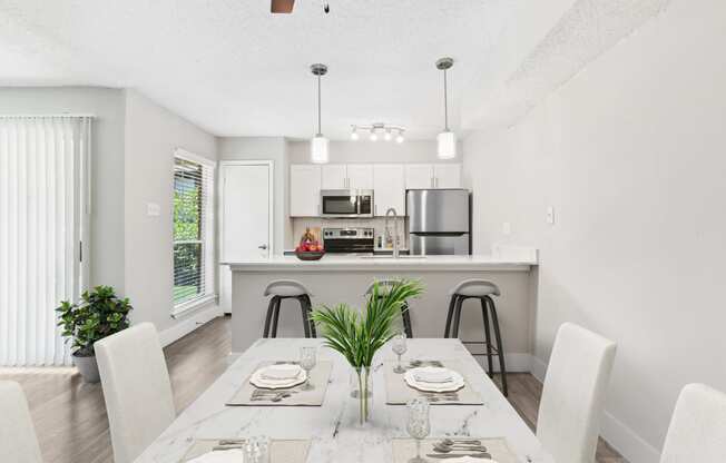 a dining area with a table and chairs and a kitchen in the background