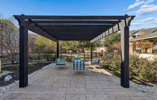 A patio with a black pergola and blue and white striped chairs.