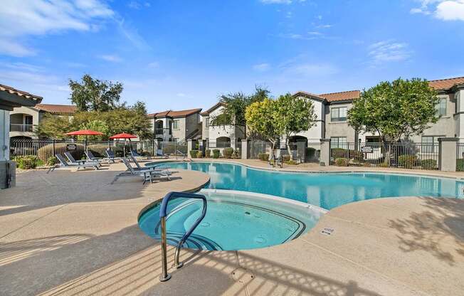 A swimming pool surrounded by chairs and buildings.