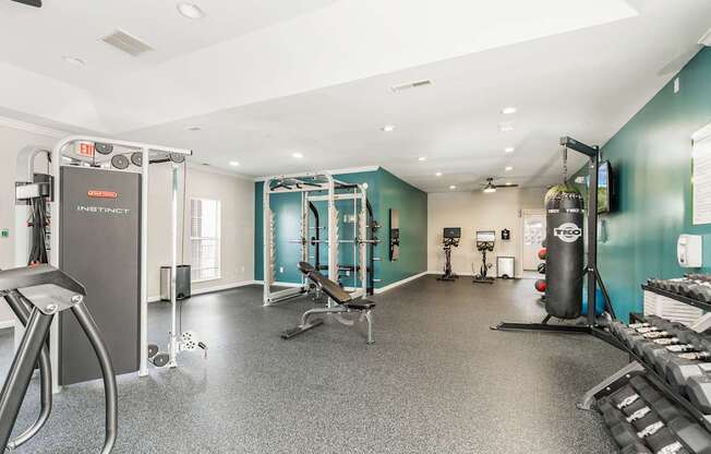 a gym with weights and cardio equipment on the floor and a wall with a blue