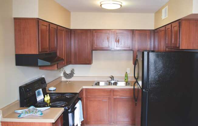 a kitchen with wooden cabinets and a black refrigerator