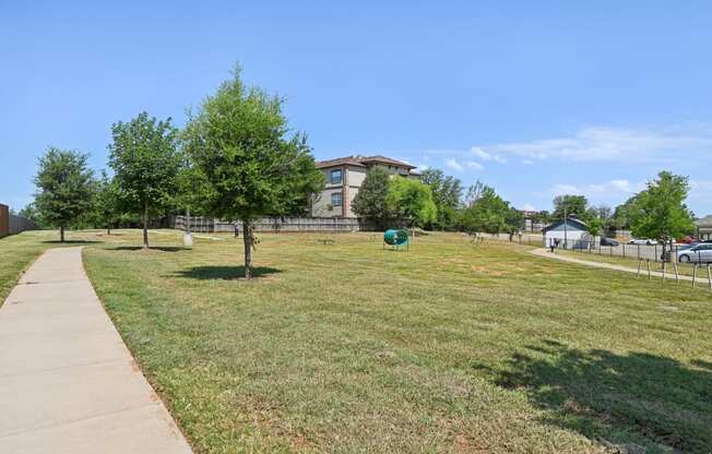 a park with grass and trees in front of a building