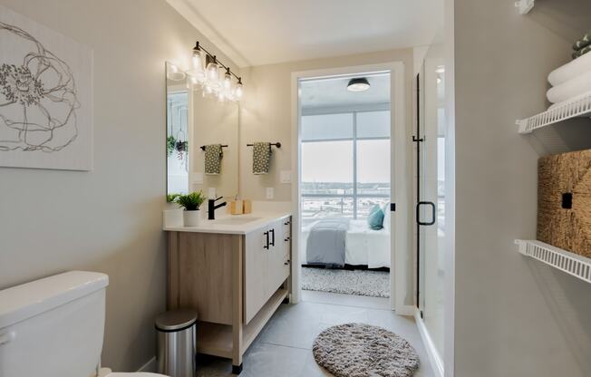 a bathroom with a toilet and a sink and a door to a bedroom at One Foundry Way, St. Louis, MO