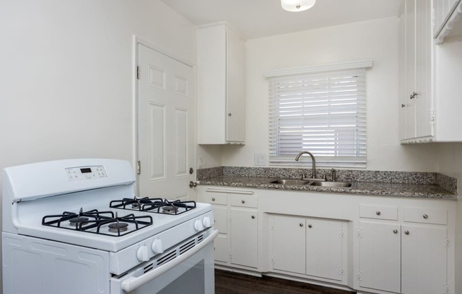 a kitchen with white appliances and granite counter tops and white cabinets