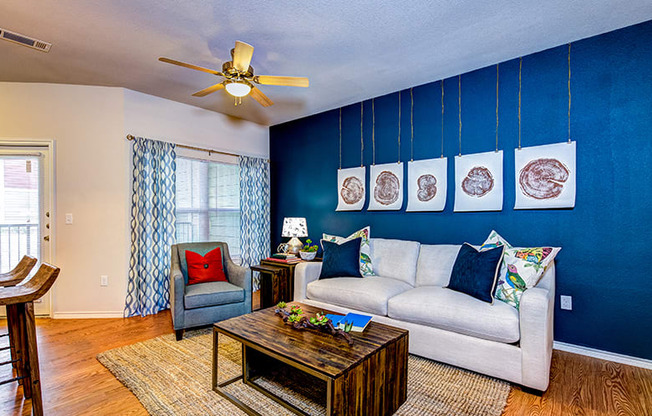 a living room with a blue accent wall and a white couch at Villa Espada Apartments, Texas, 78221