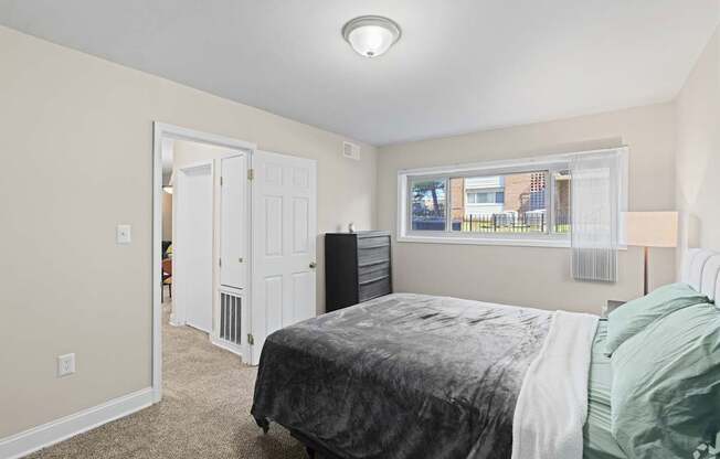 A bedroom with a bed, dresser, and window.