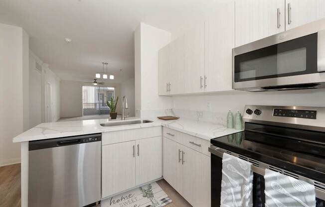A modern kitchen with white cabinets and stainless steel appliances.