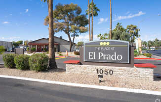 A sign for The Place at El Prado stands in front of a building.