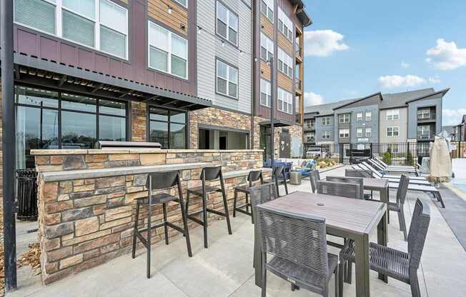 a patio with tables and chairs in front of a building at The Quarry Luxury Apartment Homes, Colorado