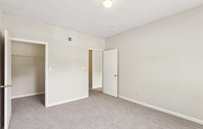 an empty bedroom with a closet and an open door