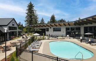 a swimming pool with lounge chairs and umbrellas in front of a building