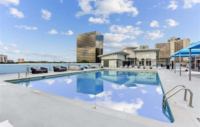 A swimming pool with a blue sky and clouds reflected in the water.