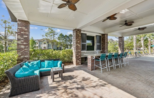 A patio with a couch, chairs, and a table under a roof.