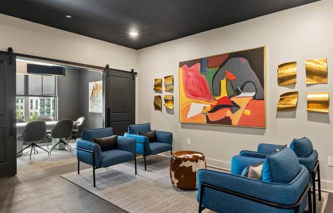 A living room with a blue couch and a painting on the wall.