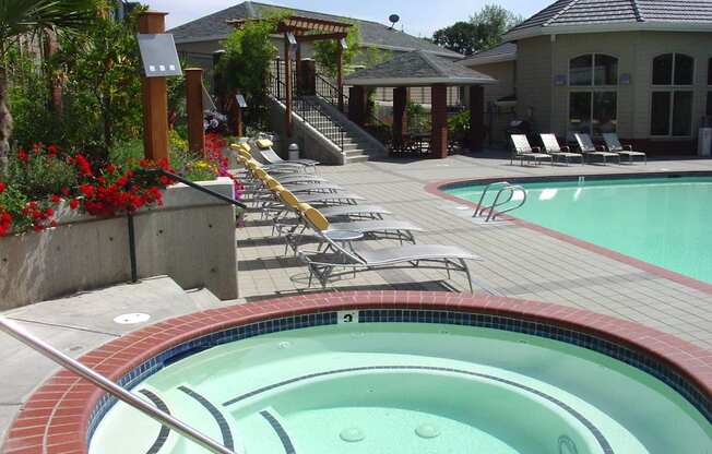 A hot tub sits in the middle of a pool surrounded by chairs at Wilsonville Summit Apartments, Wilsonville , OR