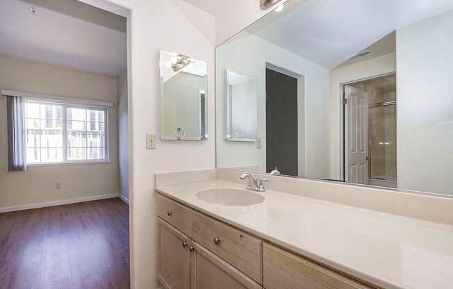 A bathroom with a sink, mirror, and wooden floors.