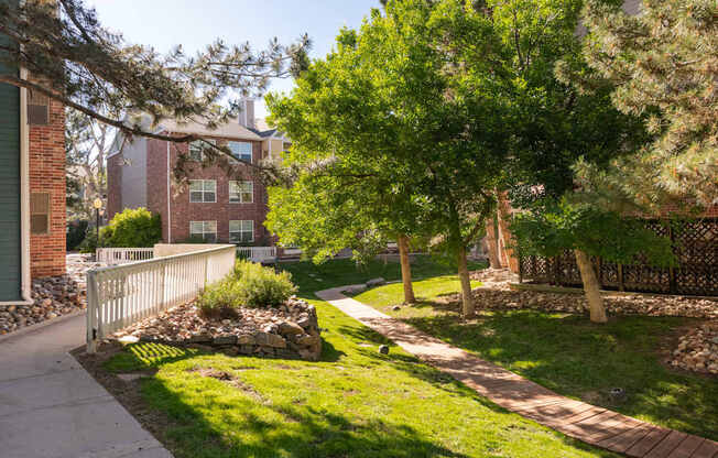 a sidewalk and trees in front of a brick building