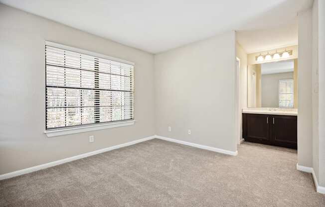 an empty bedroom with a large window and a bathroom