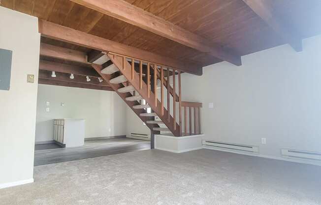a large room with a wooden ceiling and stairs to the second floor
