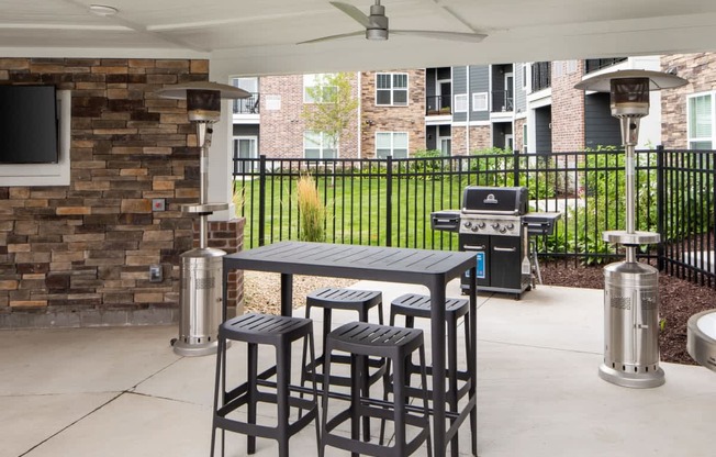 A patio with a table and chairs and a grill.