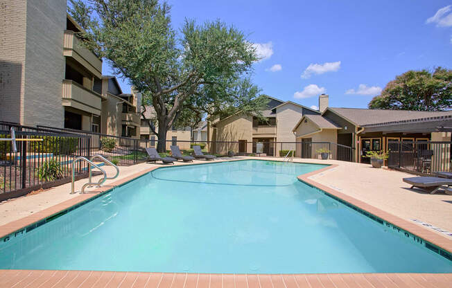 A large swimming pool surrounded by a fence and buildings.